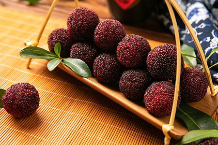 Ripe blackberries with leaves in a basket on a bamboo mat