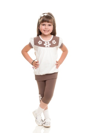 cute little girl standing and smiling against white backgroundの写真素材