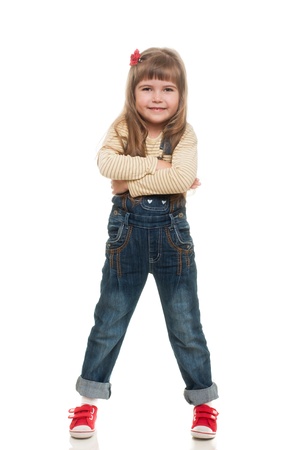 cute little girl wearing jeans overall posing in studio and smiling on white backgroundの写真素材
