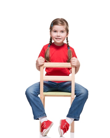 little girl wearing red t-short and posing on chair on white backgroundの写真素材