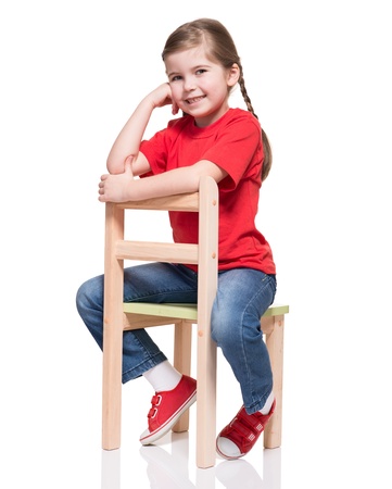 little girl wearing red t-short and posing on chair on white backgroundの写真素材