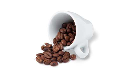 little cup with scattered coffee beans lying on white backgroundの写真素材