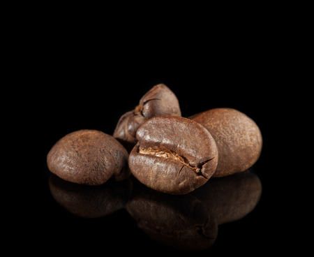 closeup of some roasted coffee beans on blackの写真素材