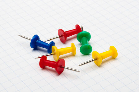 few colorful pins lying on sheet white of paperの写真素材