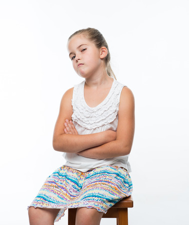 little girl sitting on chair and grins mischievously to the cameraの写真素材