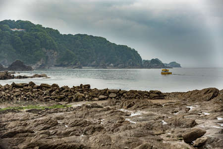 landscape of a small boat in a sea bay showing the rocky beach and cliffs in the distance