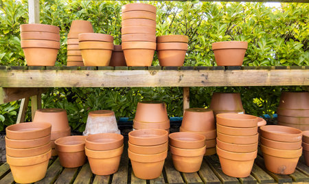 Stacks of various terracotta pots for plants for sale at a garden store.の写真素材