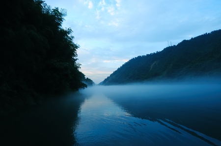 River landscape at sunset with fog rolling across the chilly river water, photo taken in Hunan province of Chinaの写真素材
