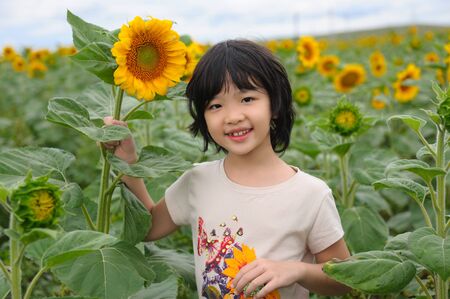 Chinese little kid smiling in the sunflower fieldの写真素材