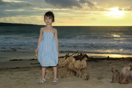 A Chinese little kid standing on Jimbaran beach at sunset, Bali, Indonesia の写真素材
