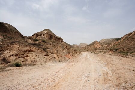 Road on the foot of earth hills in Chinese rural areaの写真素材