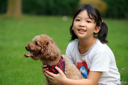 Asian kid sitting and holding a poodle dogの写真素材