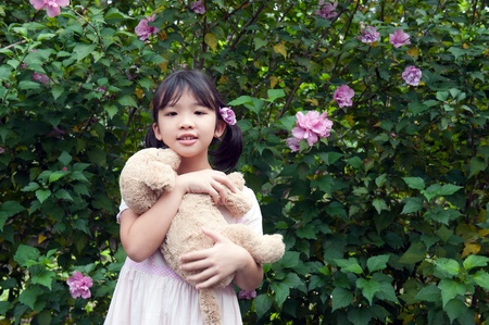 Asian kid standing and holding a toy dogの写真素材