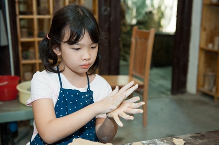 Asian kid shaping pottery in the studioの写真素材