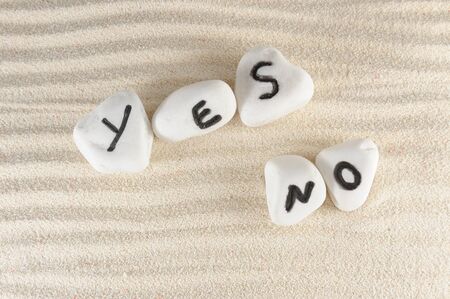 Yes no words carved on stones of the beachの写真素材