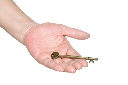Hand passing an old key isolated on white backgroundの写真素材
