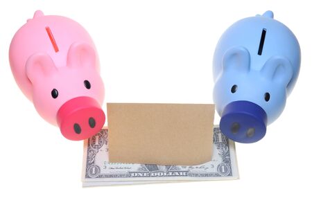 Two piggy banks standing side by side with dollar bills and a blank paperの写真素材