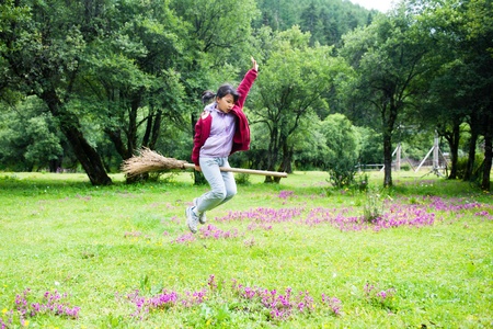 Asian kid jumping on the meadow  in rural area of Shangri-La county,Yunnan province, Chinaの写真素材