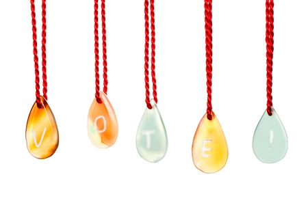 Vote word spelled with agates that are engraved with white letters and are hung by ropes, isolated against white backgroundの写真素材