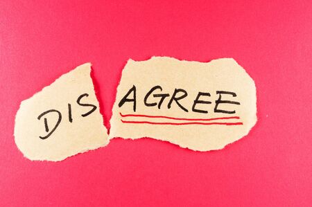 Disagree to agree concept words written on the paper against red backgroundの写真素材