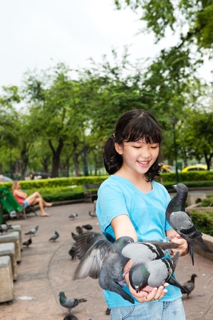 Asian kid feeding pigeons in the parkの写真素材