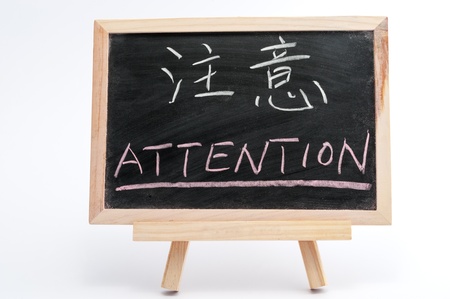Bilingual word of Attention in both Chinese and English written on blackboard over white backgroundの写真素材