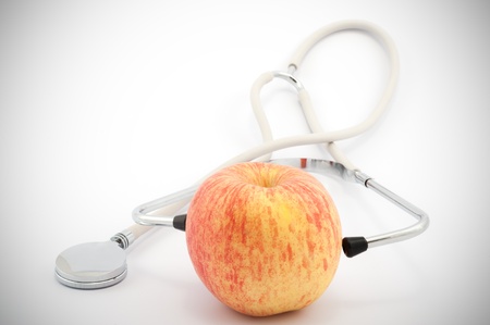 Using stethoscope to examine an apple on white backgroundの写真素材