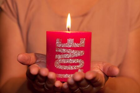 Two hands holding a big red candleの写真素材
