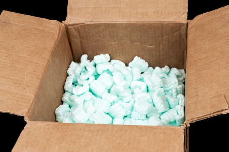 Cardboard box filled with styrofoam shipping peanuts isolated on black backgroundの写真素材