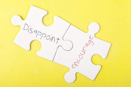 Disappoint and Encourage words written on two pieces of jigsaw puzzleの写真素材