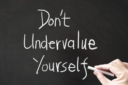Don't undervalue yourself words written on the blackboard using chalkの写真素材