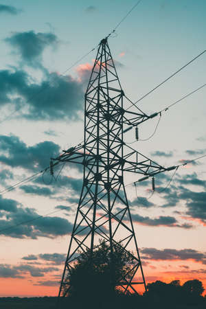 High voltage electrical pole against sunset sky. Vertical orientation