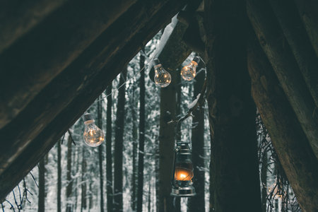 Garlands and kerosene lamp hanging on survival shelter in winter forestの写真素材