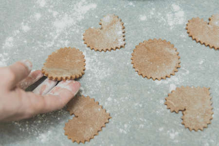 Process of cutting cookies by cookie cutters. Woman making by hands forms for cookies from raw dough