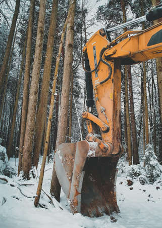 Large orange excavator bucket covered with snow in winter forest. Vertical orientationの写真素材