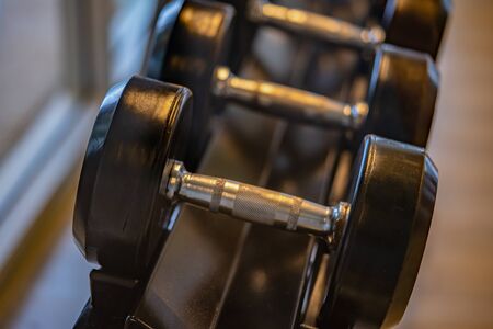 Black dumbbell set. Close up many metal dumbbells on rack in sport fitness center , Weight Training Equipment concept.の写真素材