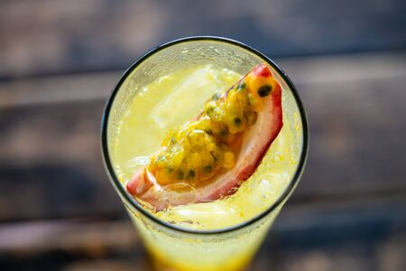 Passion fruit lemonade in a clear glass in a summer cafe. the view from the top. slice close up. background - wooden tableの写真素材