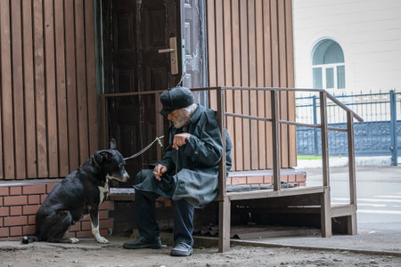a solitary grandfather with his dog sits sad and smokes cigaretteのeditorial素材