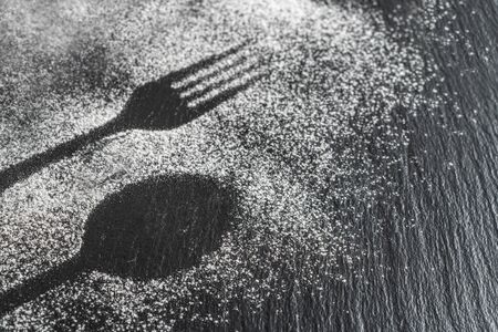 Spoon, fork silhouette made with flour on dark texture background, up horizontal view