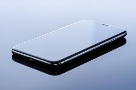 mobile phone on glass surface with beautiful gradient and gray background, close up.