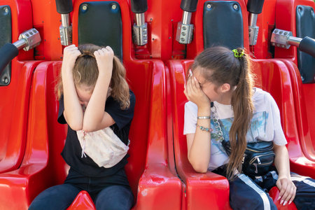 Two girls on the attraction are afraid and cover their heads with their handsのeditorial素材