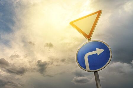 Give way and turn right, against the backdrop of dramatic sky and cloudsの写真素材