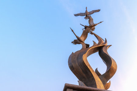 Krasnoyarsk, Russia, September 1, 2019: Three swans, a fragment of a bronze monument, against a blue sky, close-upのeditorial素材