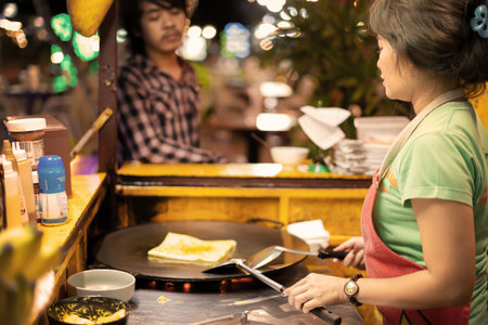 Khaolak, Thailand, 5 june 2019: ute Thai woman cooking and selling traditional Thai sweet pancakes Roti on the street of Khao Lak in Thailand.のeditorial素材