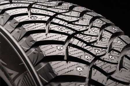 new winter studded tire Dunlop Winter Ice 03 on a black background, square powerful spikes....