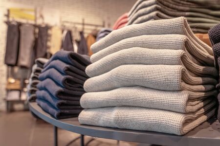 a stack of clothes in the store, pullovers and sweatshirts nicely and neatly stacked in bundles on...