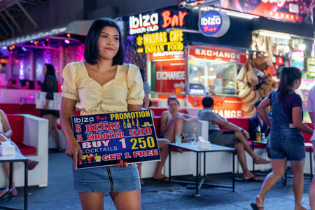 Thailand, Phuket, Patong 3 January 2020: a young pretty Thai girl, a waitress and a Barker on Bangla road, invites tourists to her restaurant, cafe and night barのeditorial素材