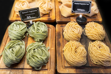 Thailand, Phuket, January 1, 2020: Tagliatelle spinach and Roasted vegetables tart on wooden trays in the store. Italian raw pastaのeditorial素材