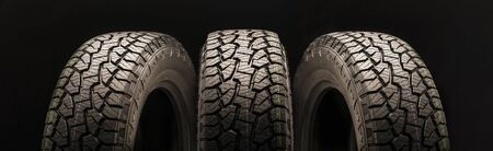 mud all terrain tires for SUVs on a black background close-up, three wheels on a long layout look in...
