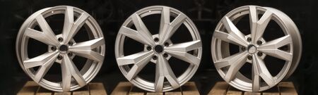 three silvery new cast aluminum wheels on a black background close-up, long layout